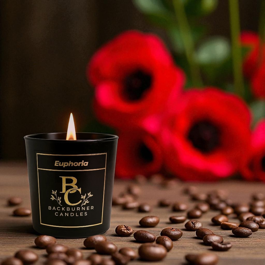 Euphoria candle in black glass jar by Backburner Candles in front of red flowers and coffee beans.