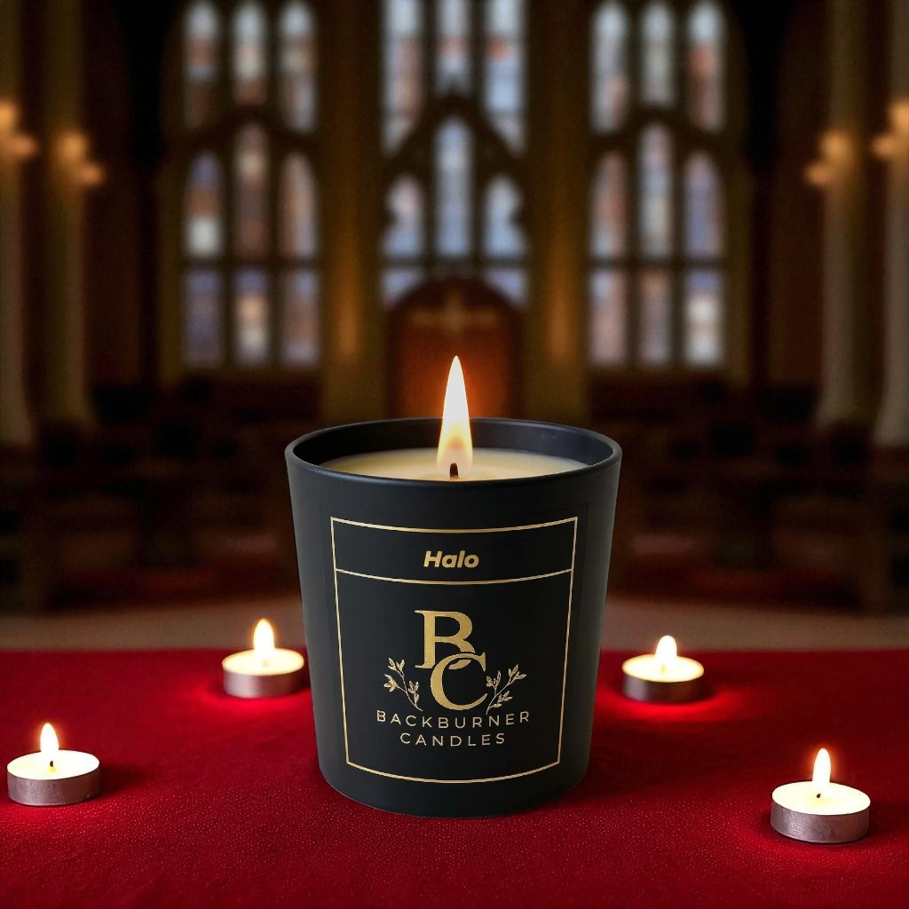 Halo candle in black glass jar by Backburner Candles on a red surface with other candles.