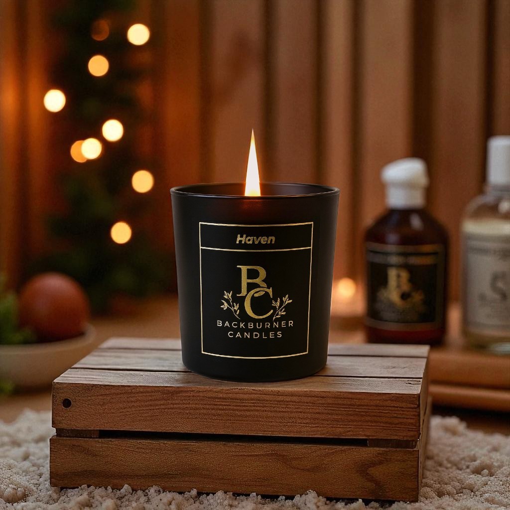 Haven candle  in black glass jar by Backburner Candlesin on a wooden crate with a warm, blurred background.