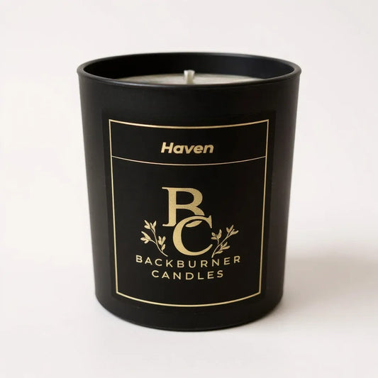 Unlit Haven vegan candle by Backburner Candles in black jar with gold logo and floral design, styled for a premium, elegant look.