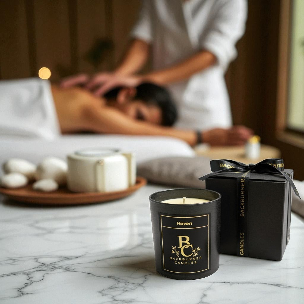Haven candle and gift box by Backburner Candles on a marble surface with a blurred massage scene in the background