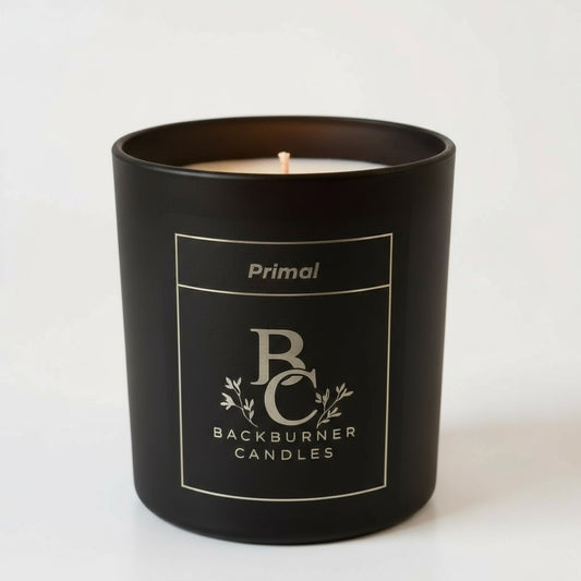 Unlit Primal vegan candle by Backburner Candles in black jar with gold logo and floral design, styled for a premium, elegant look.