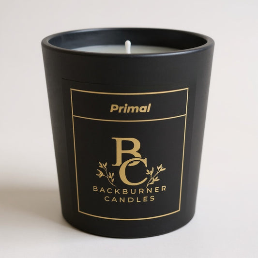 Unlit Primal vegan candle by Backburner Candles in black jar with gold logo and floral design, styled for a premium, elegant look.