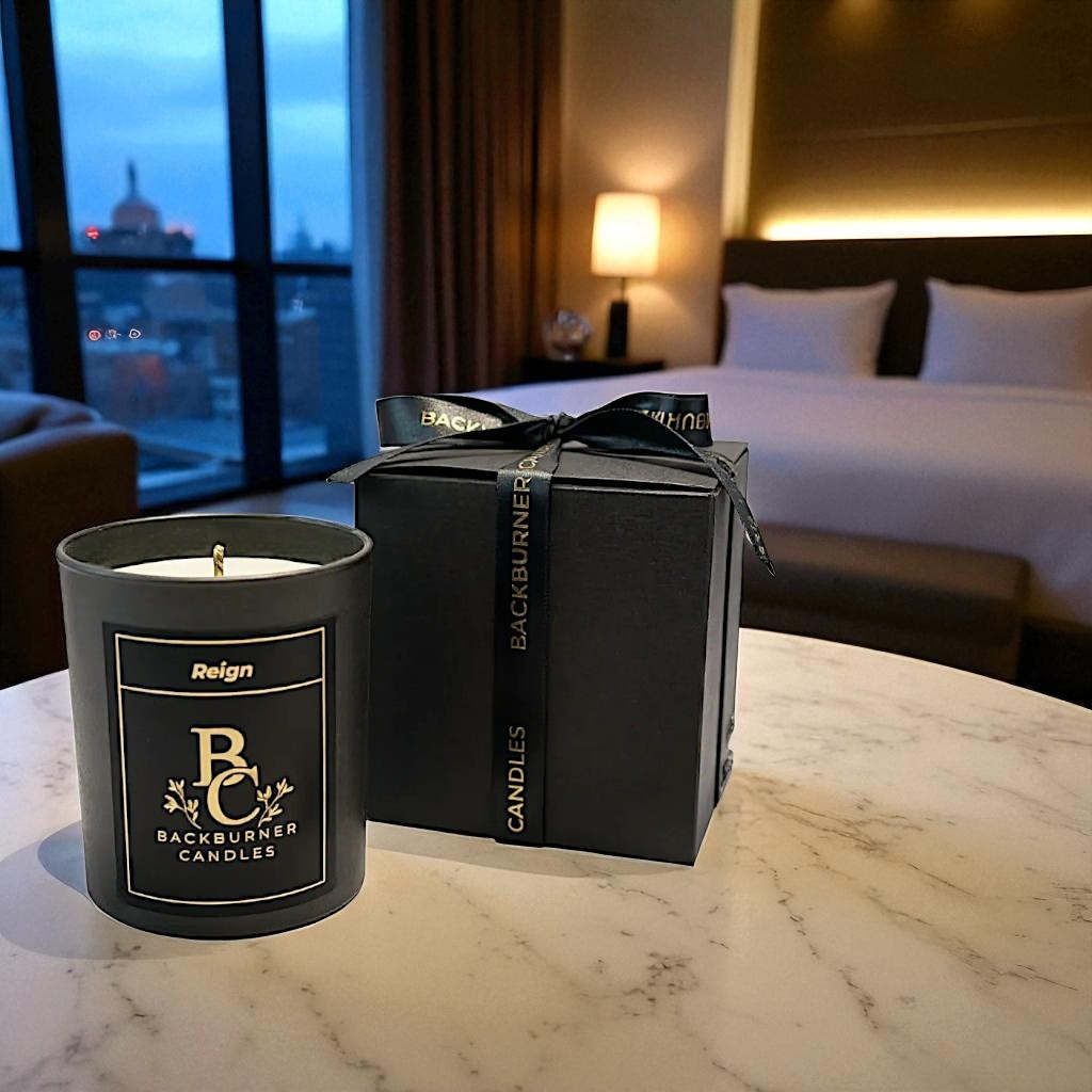 Backburner Candles candle Reign and packaging on a marble table with a bedroom in the background