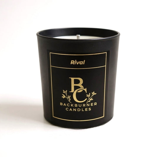 Unlit Rival vegan candle by Backburner Candles in black jar with gold logo and floral design, styled for a premium, elegant look.