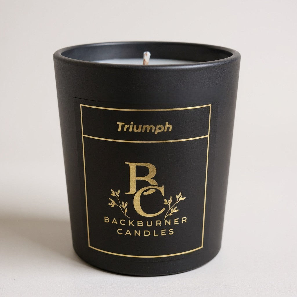 Unlit Triumph vegan candle by Backburner Candles in black jar with gold logo, styled for elegant branding and minimalist luxury.