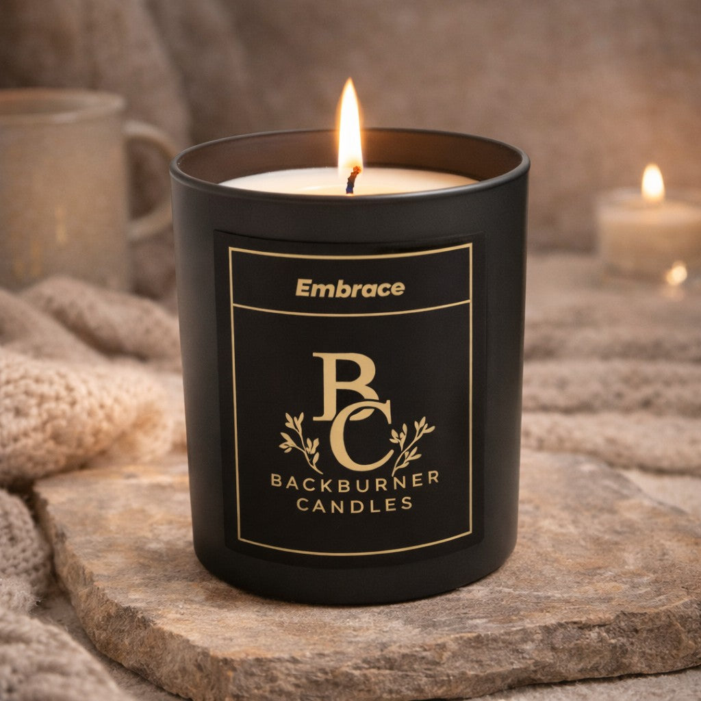 Black candle in a container with 'Backburner Candles' branding on a stone surface.