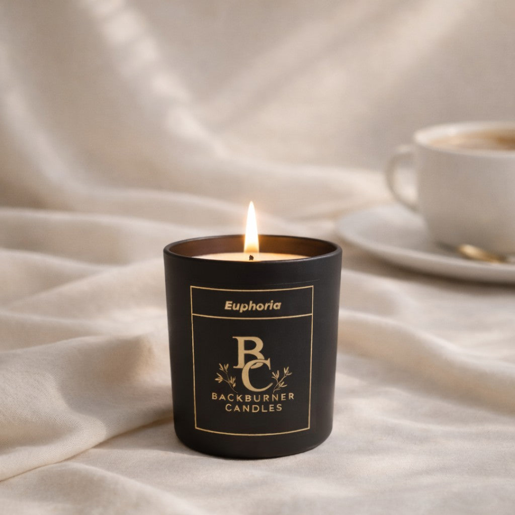 Black candle with 'Backburner Candles' branding on a white fabric background
