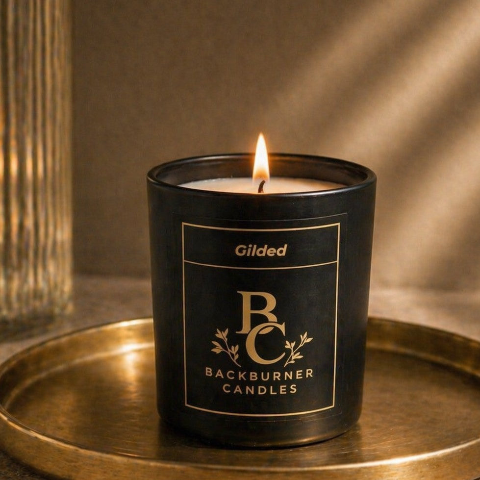 Candle in a black container with 'Backburner Candles' branding on a gold tray.