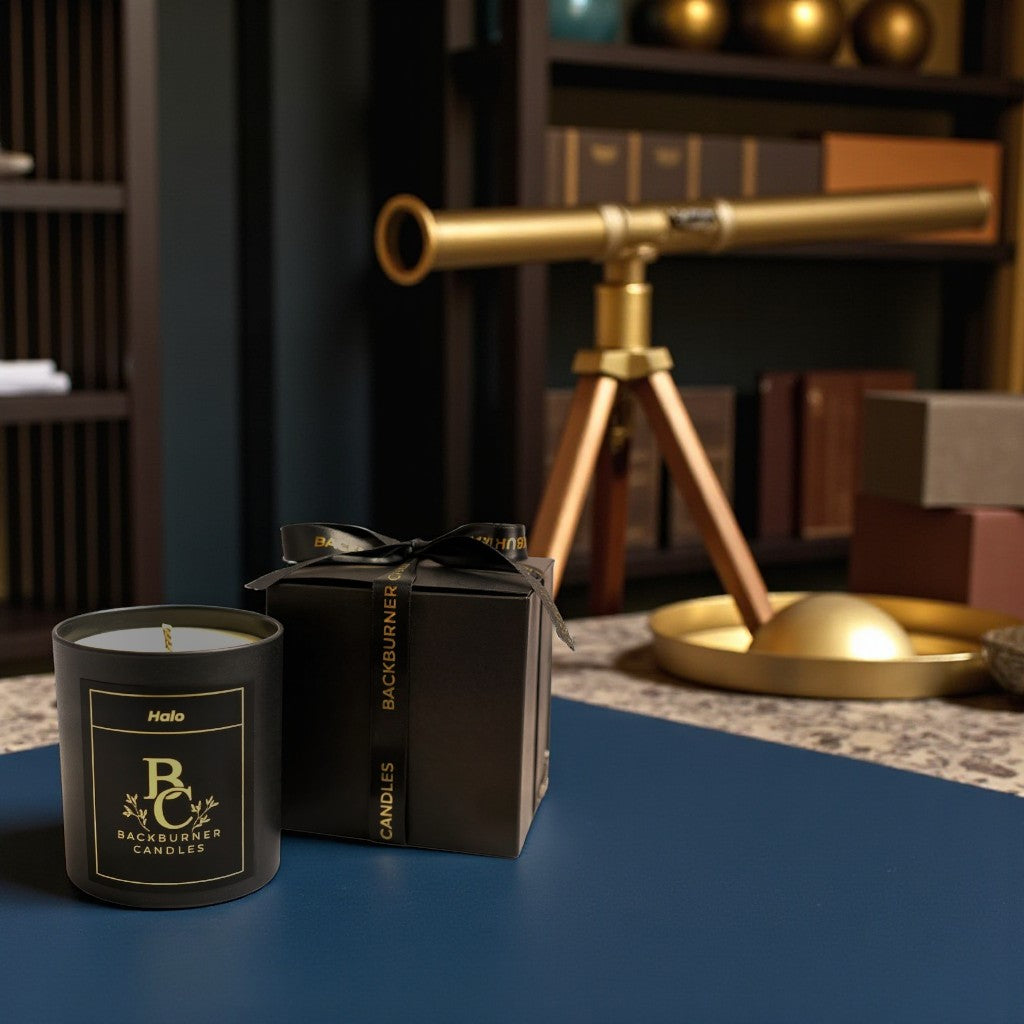 Halo candle in black glass jar by Backburner Candles and packaging on a table with a telescope in the background