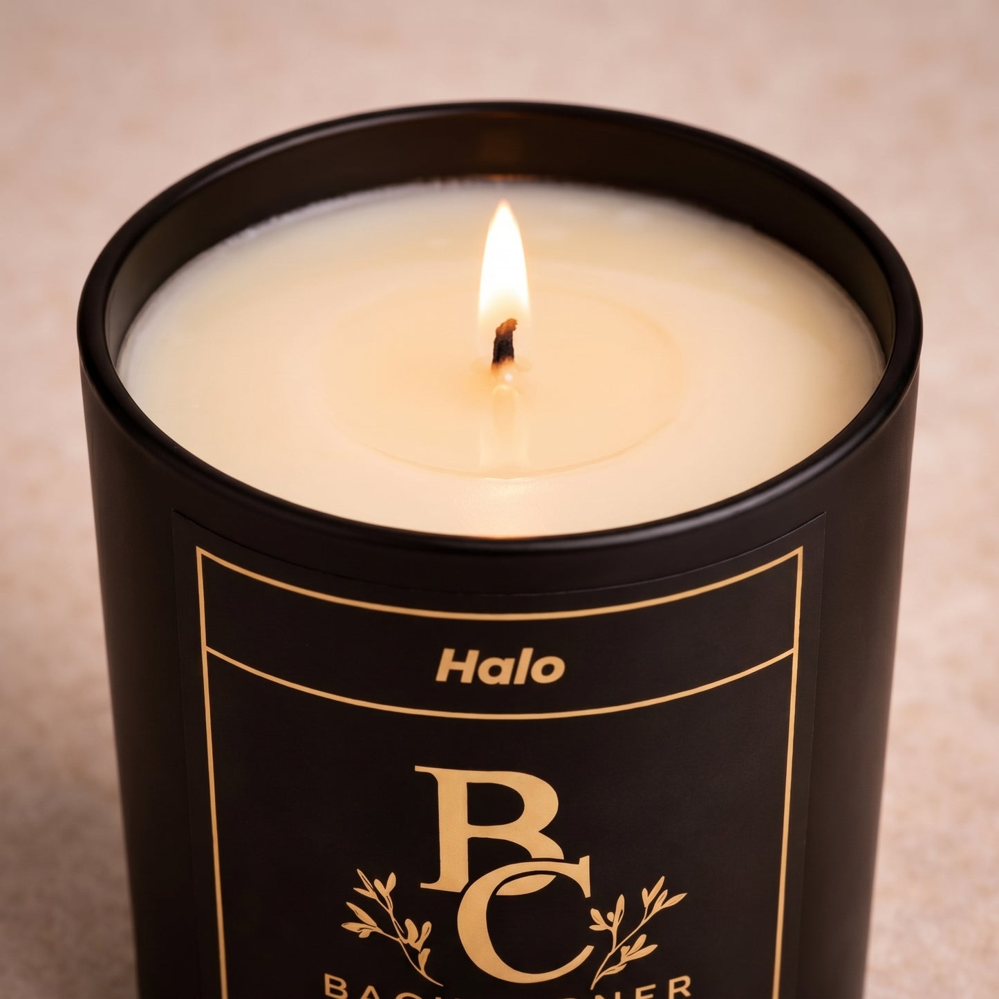 Candle in a black container labeled 'Halo' with 'BC' branding on a beige background