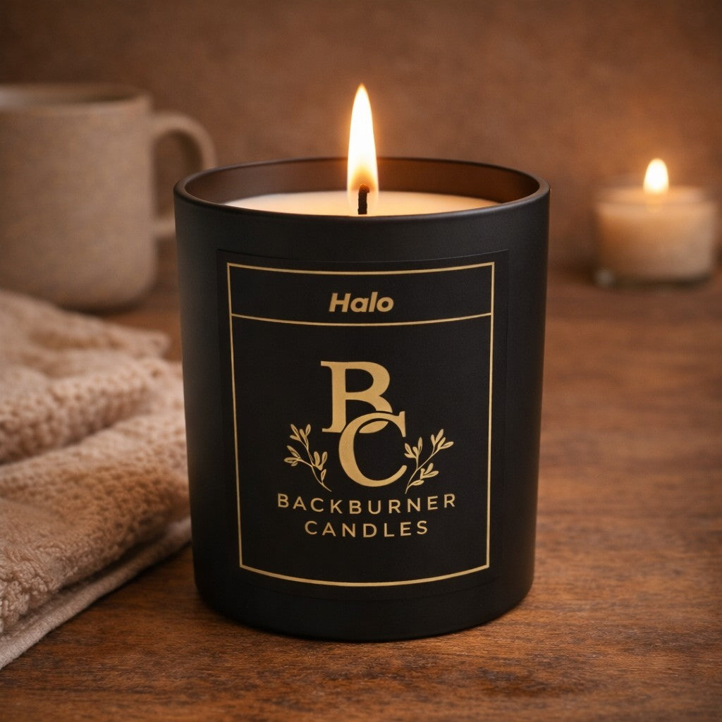 Black Halo Backburner Candles candle with a lit flame on a wooden surface.