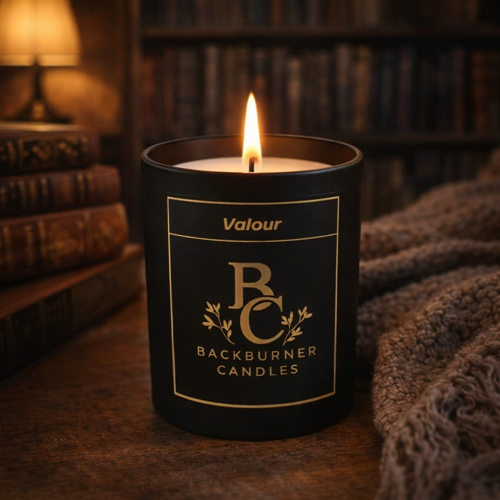 Candle in a black container with 'Backburner Candles' label, lit in a cosy room.