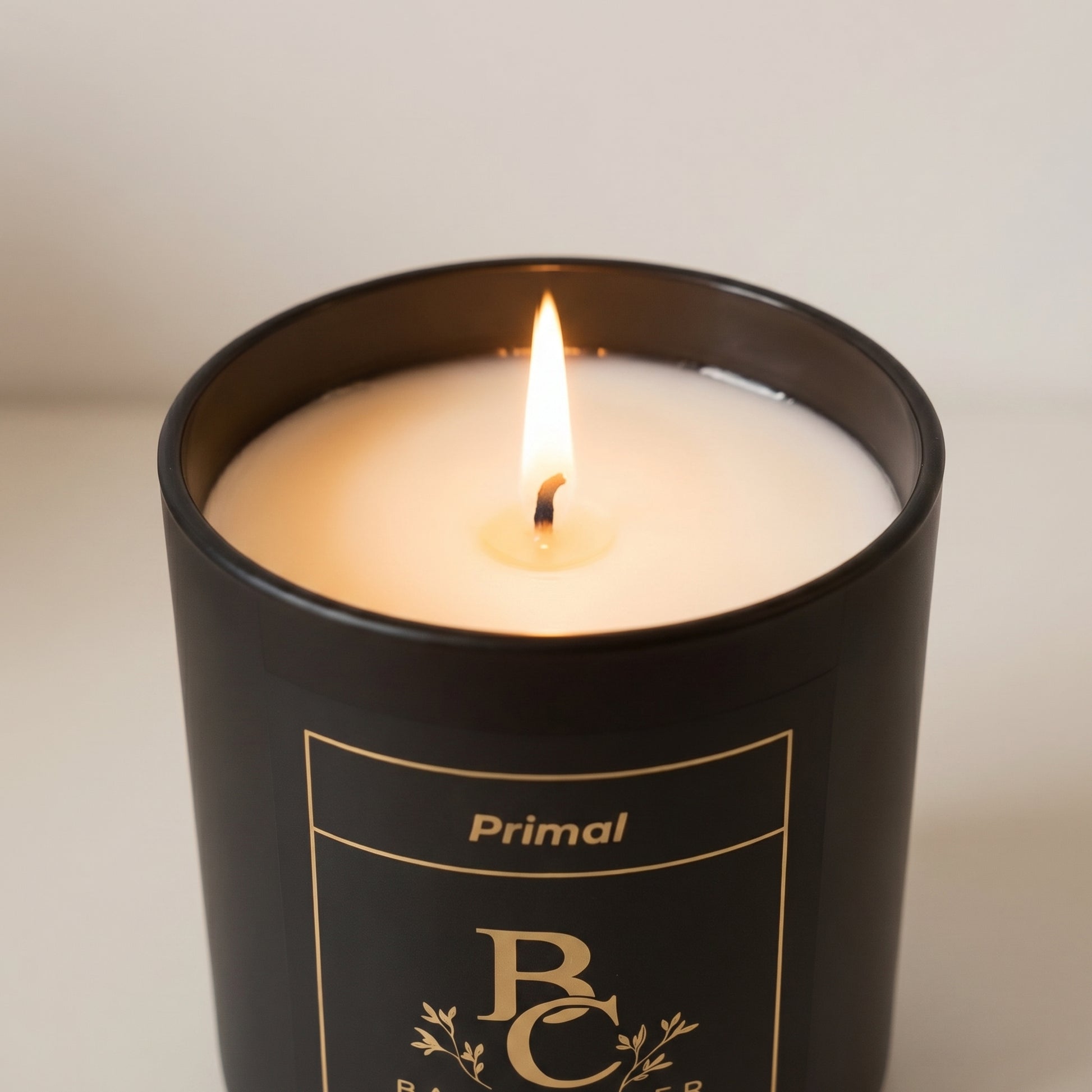Candle in a black container with 'Primal' branding on a neutral background