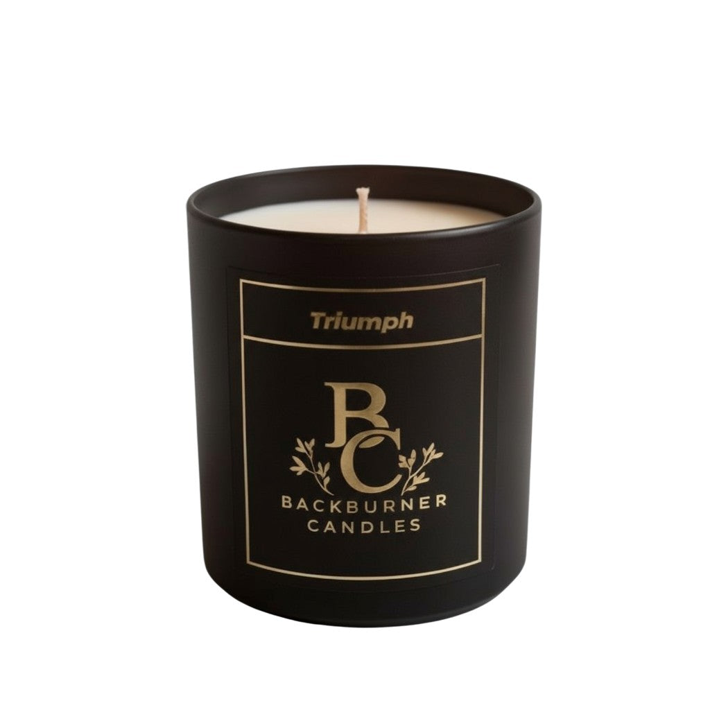 Unlit Triumph vegan candle by Backburner Candles in black jar with gold logo, styled for elegant branding and minimalist luxury.