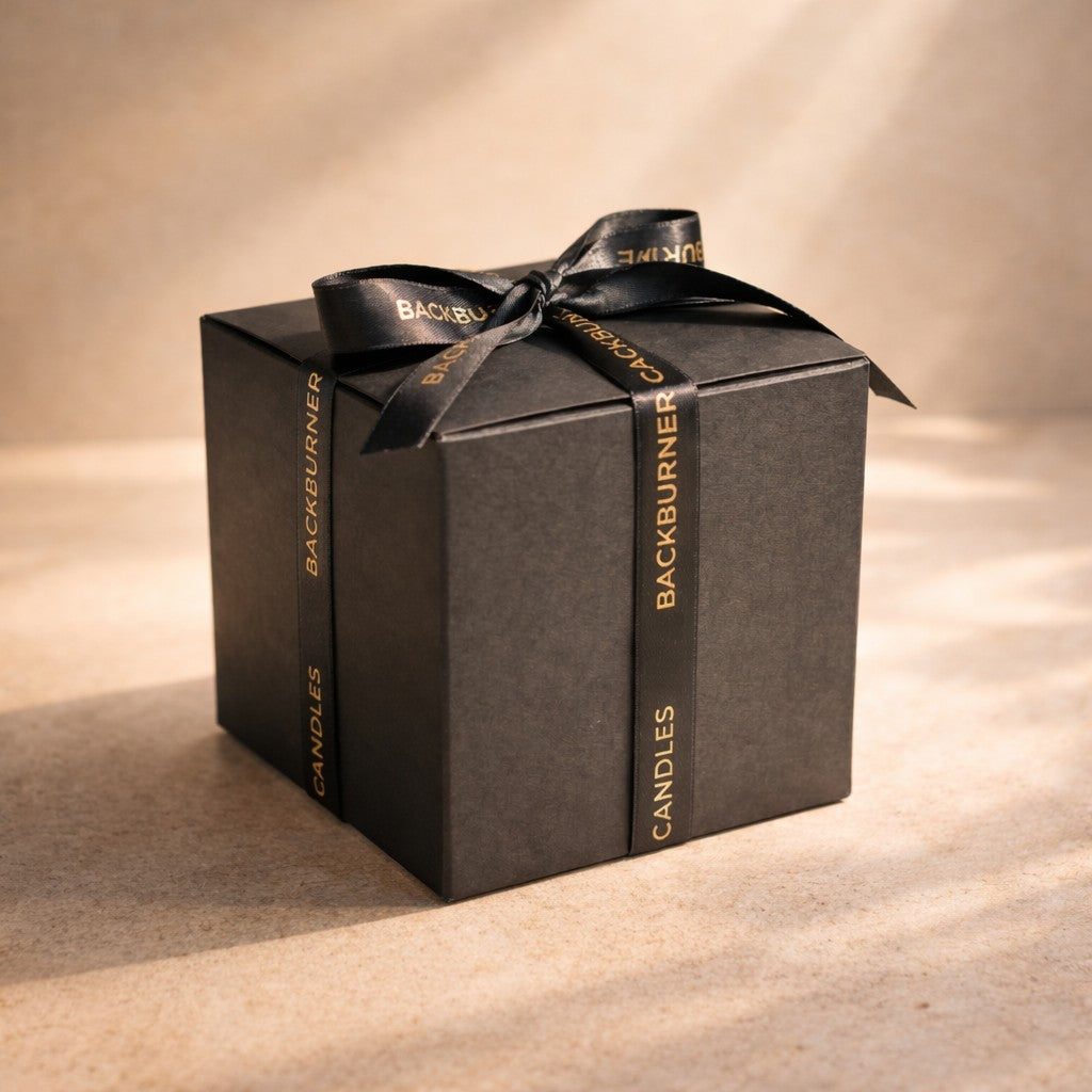 Black gift box with a black ribbon and 'Backburner Candles' branding on a beige background