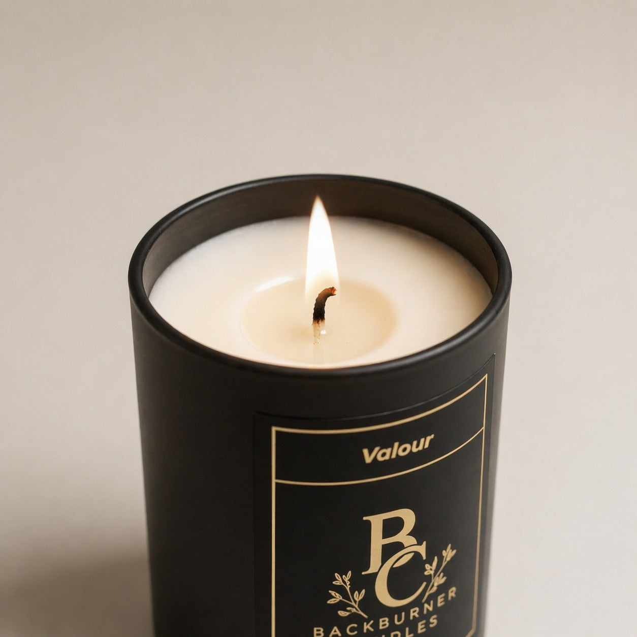 Candle in a black container with 'Valour Backburner Candles' branding on a neutral background